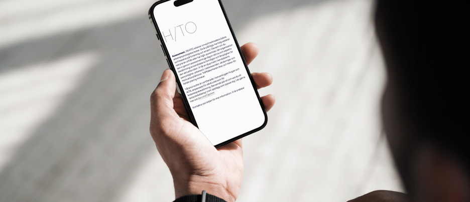 Närbild på hand som håller i mobil till Hito